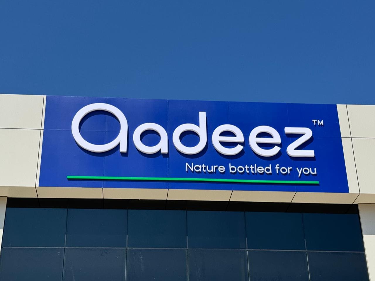 The Aadeez fascia sign on the facility building against a bright sky.