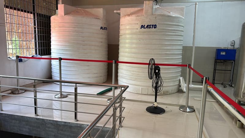 Two large white polymer storage tanks inside the facility, connected by pipework.